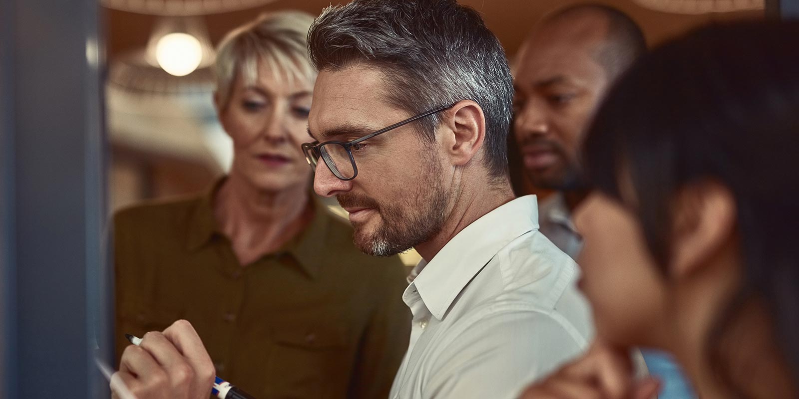 Employees in meeting writing on board.