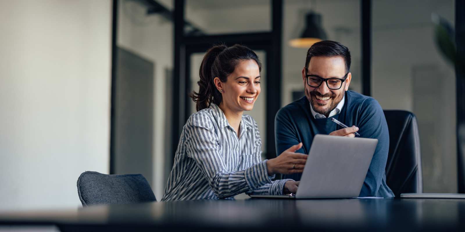 Employees in conference room looking at laptop