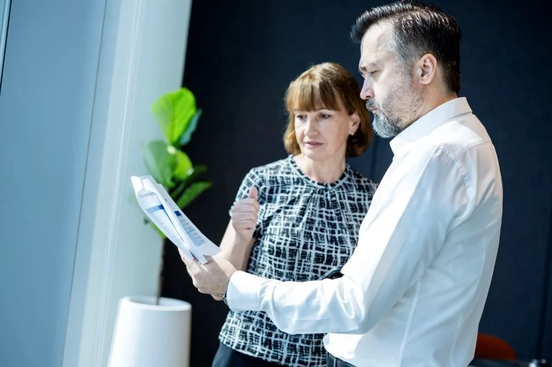 Man-and-Woman-Standing-in-Office-Reviewing-Paperwork-800-533